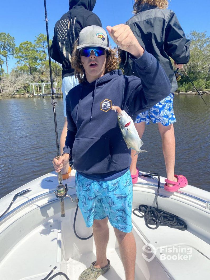 A young boy is standing on a boat holding a fish.