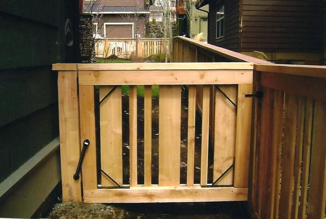 Wooden gate with vertical slats and black iron supports. Opens to a wooden deck.