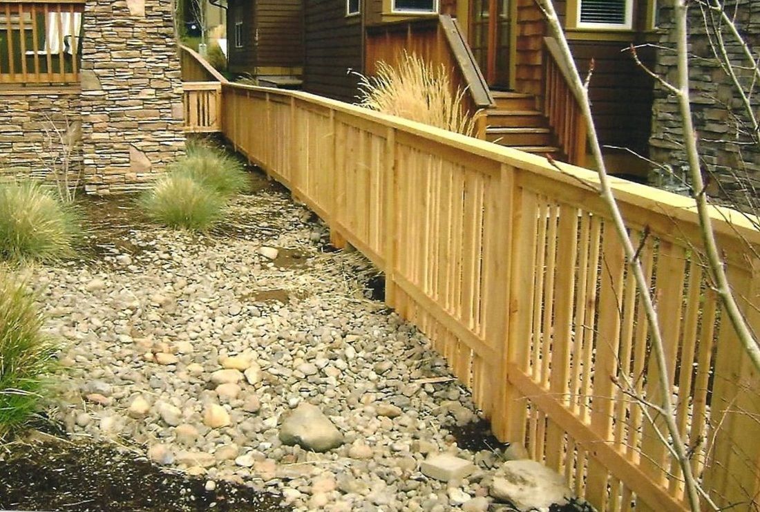 Wooden ramp with railing alongside a gravelly embankment next to a wood-sided building.