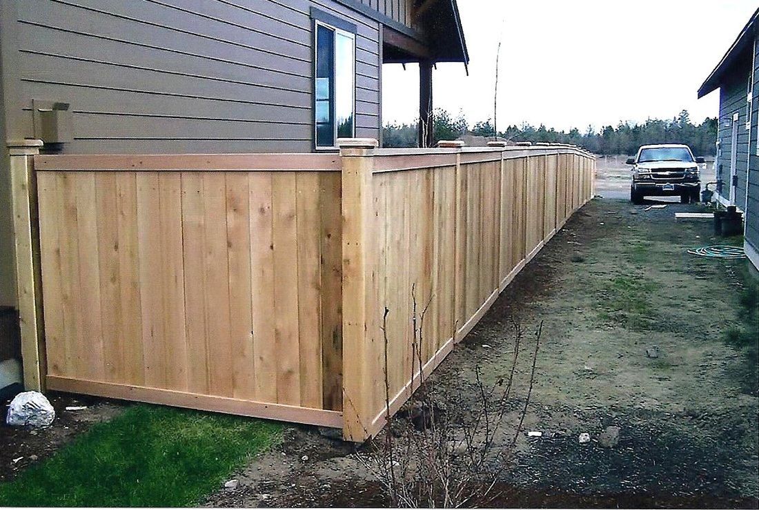 Wooden fence surrounding a building and extending along a yard.