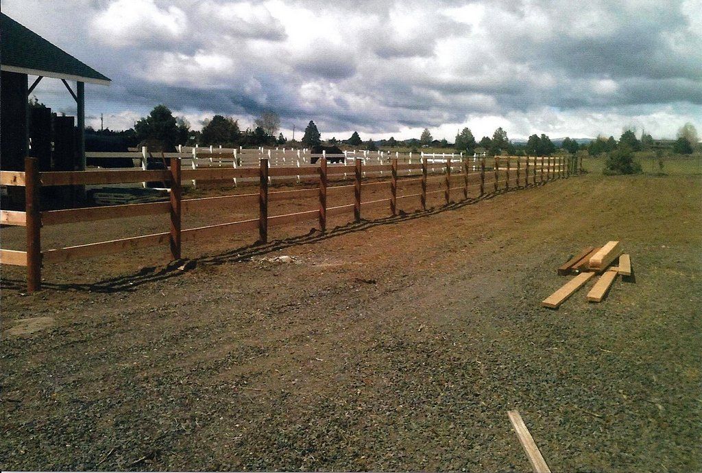Brown wooden fence in a field under a cloudy sky.