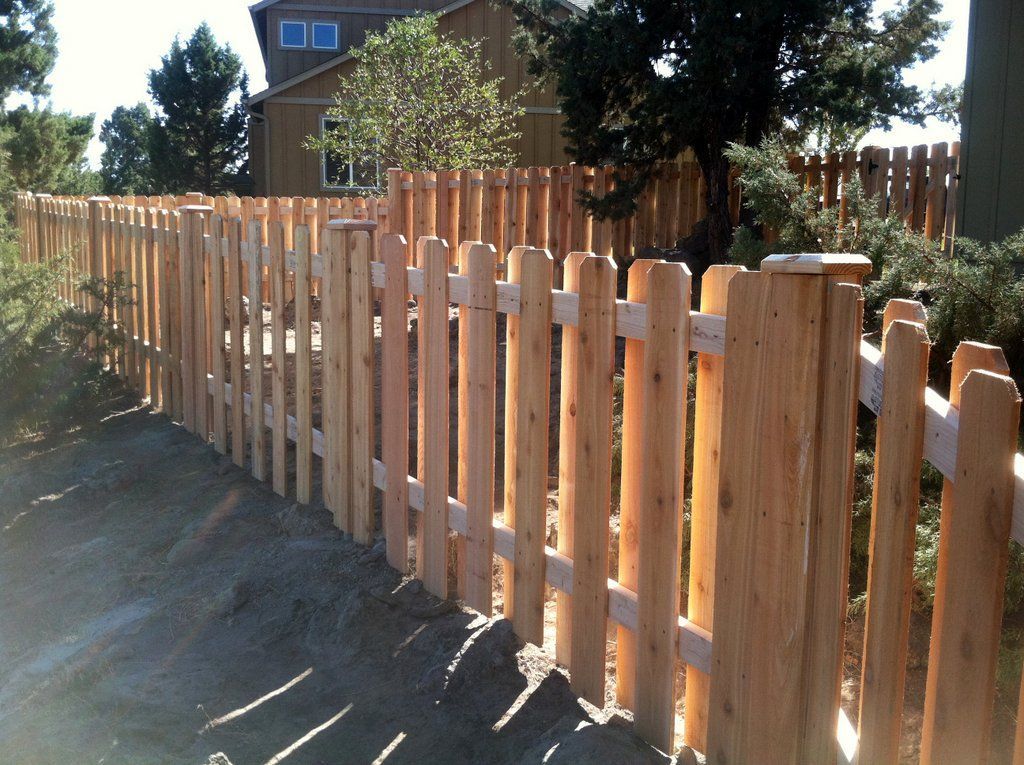 Wooden picket fence in a yard, sunny day.