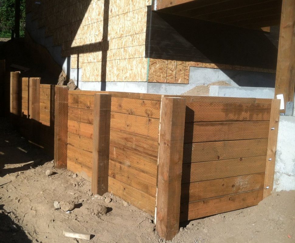 Wooden retaining wall under a building under construction, brown planks and posts.