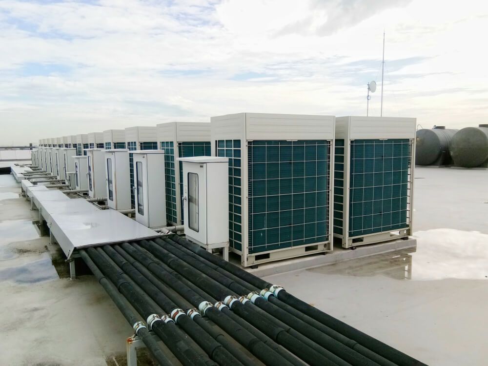 A Row of Air Conditioners Are Lined Up on the Roof of a Building — JHE Air Conditioning Services In Saratoga, NSW