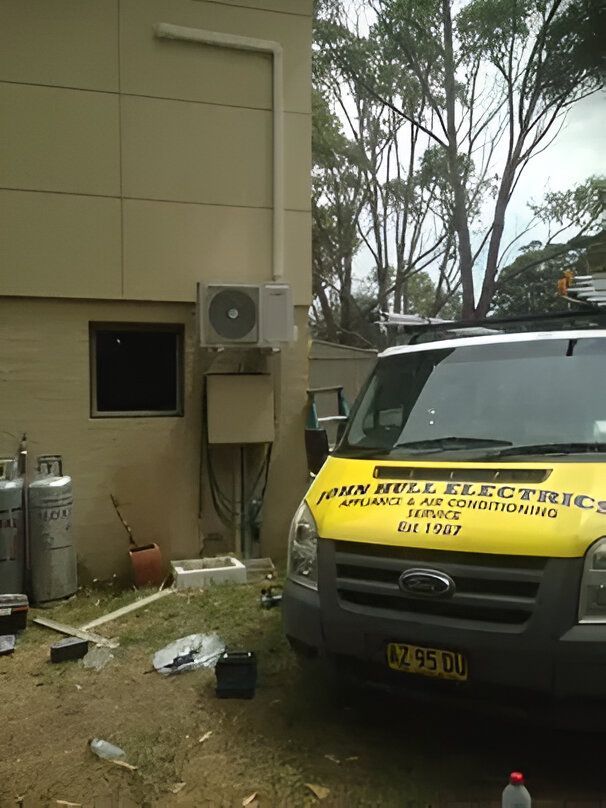 A Yellow Van is Parked in Front of a Building — JHE Air Conditioning Services In Saratoga, NSW
