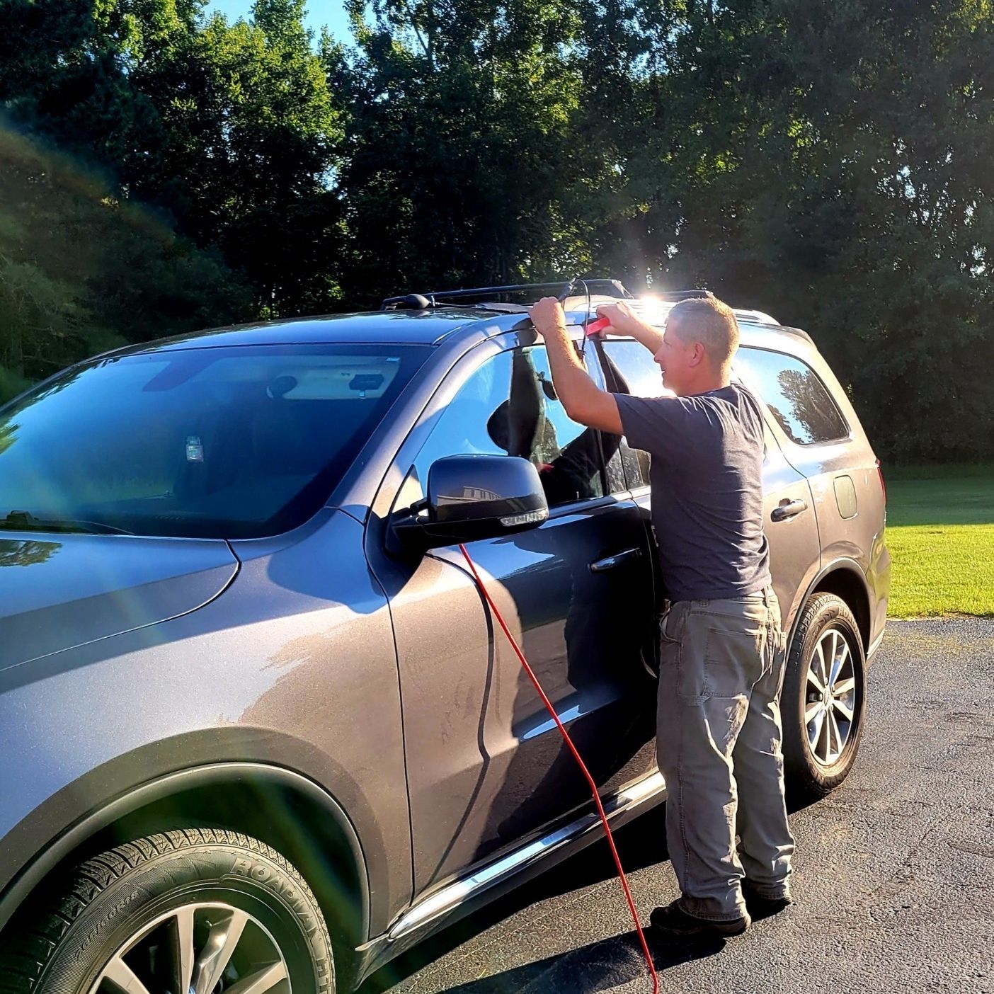 A man is standing next to a car with a hose attached to it