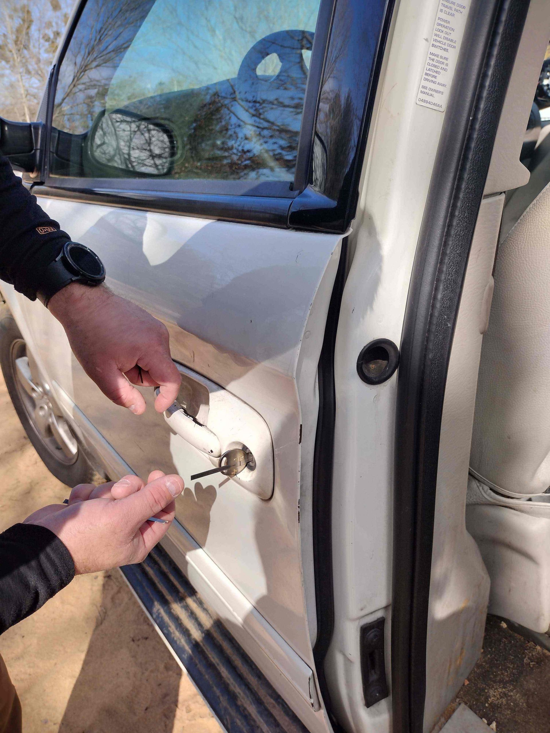 A man is opening the door of a car with a key.