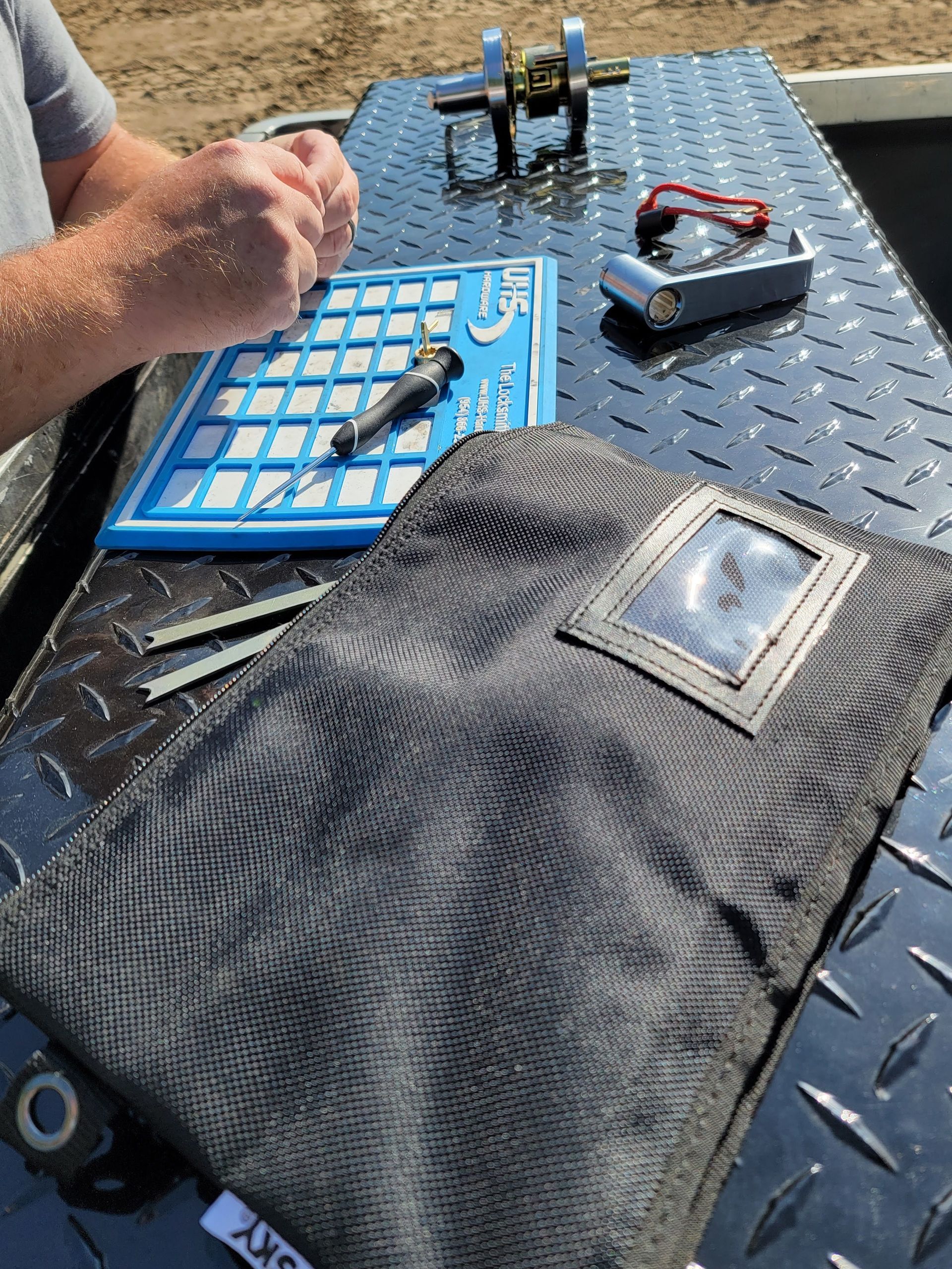 A person is sitting at a table with a bag of tools on it.