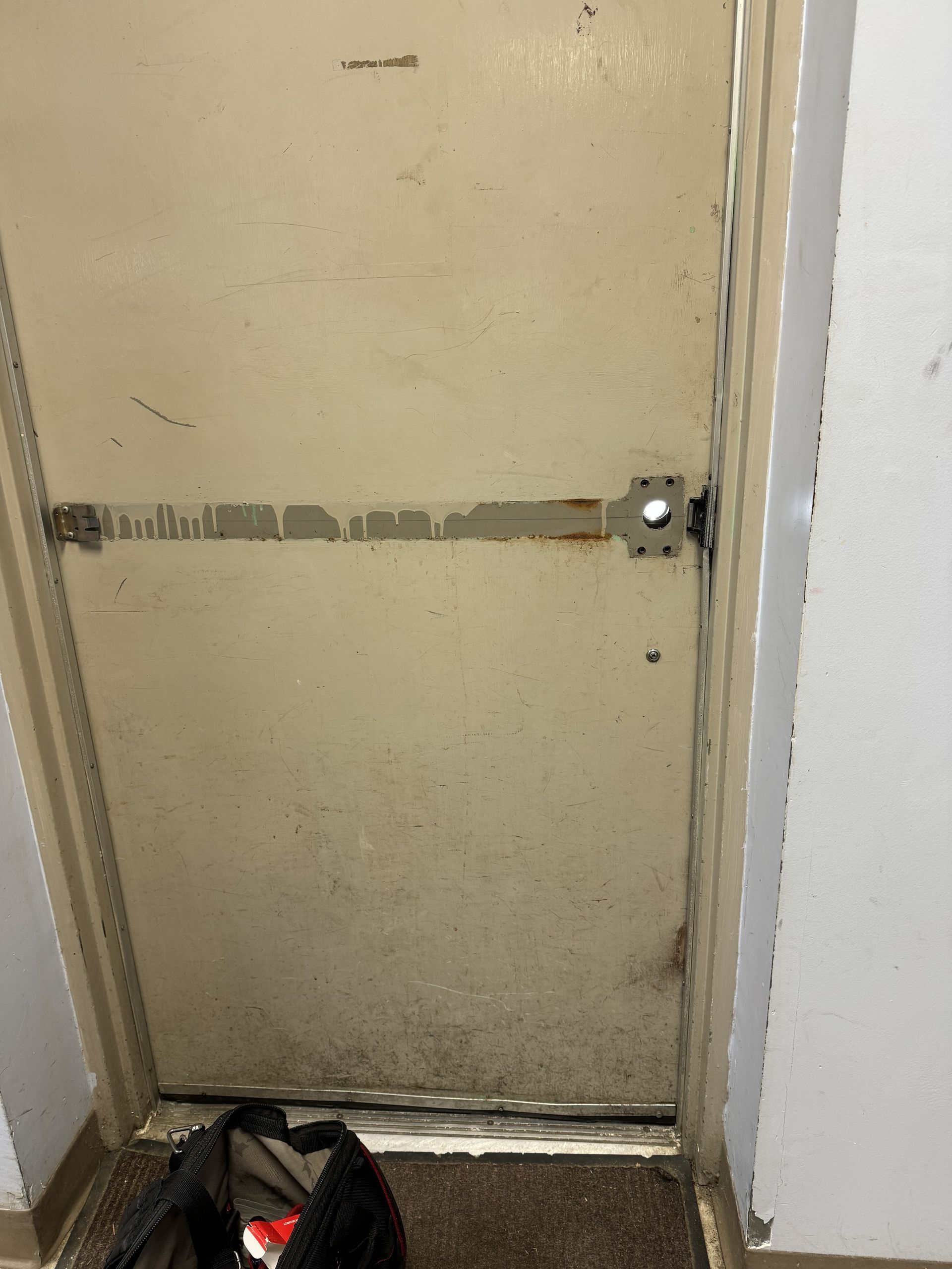 A dirty door with a lock on it in a room.