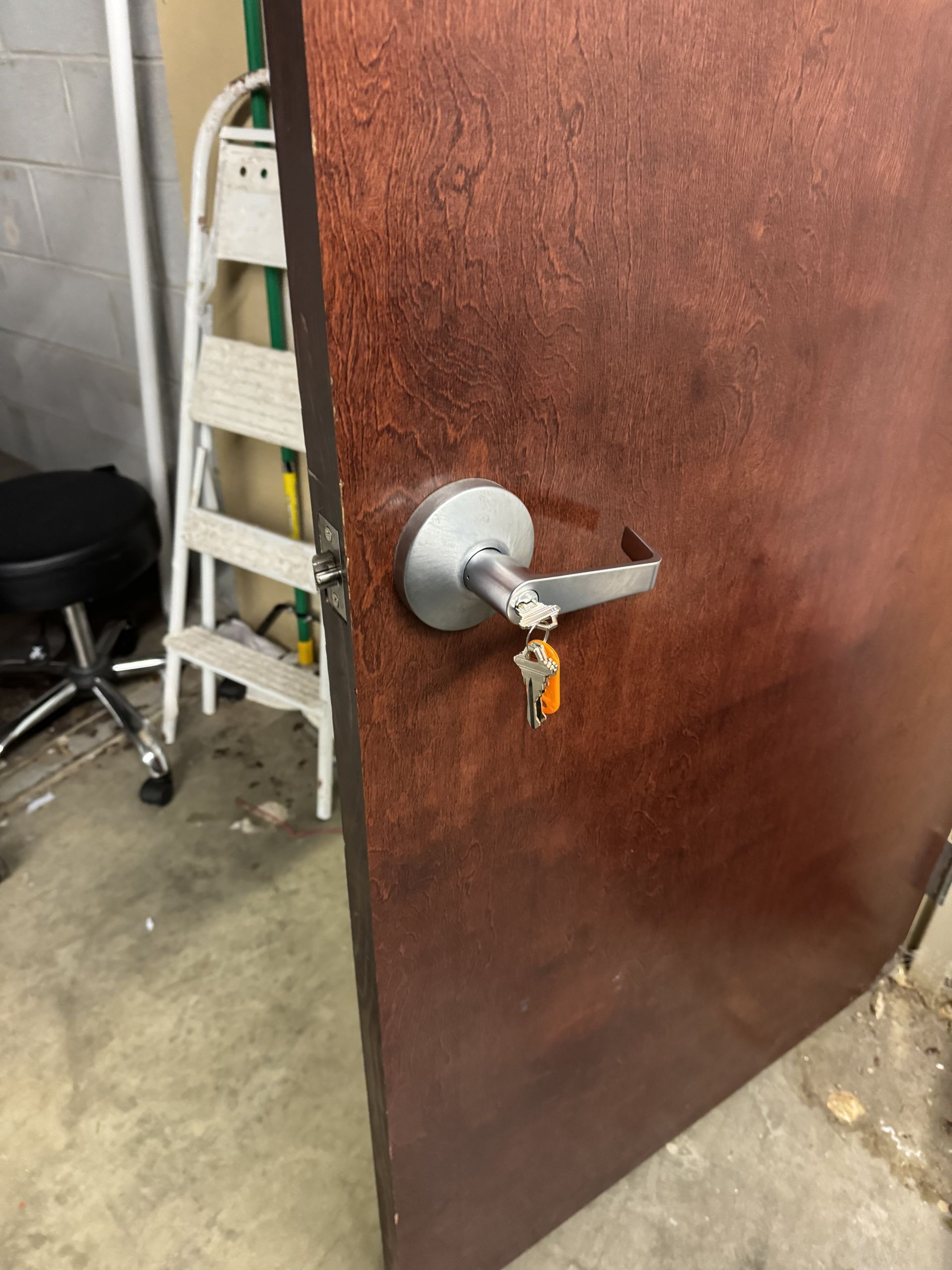 A door with a key in it and a ladder in the background.