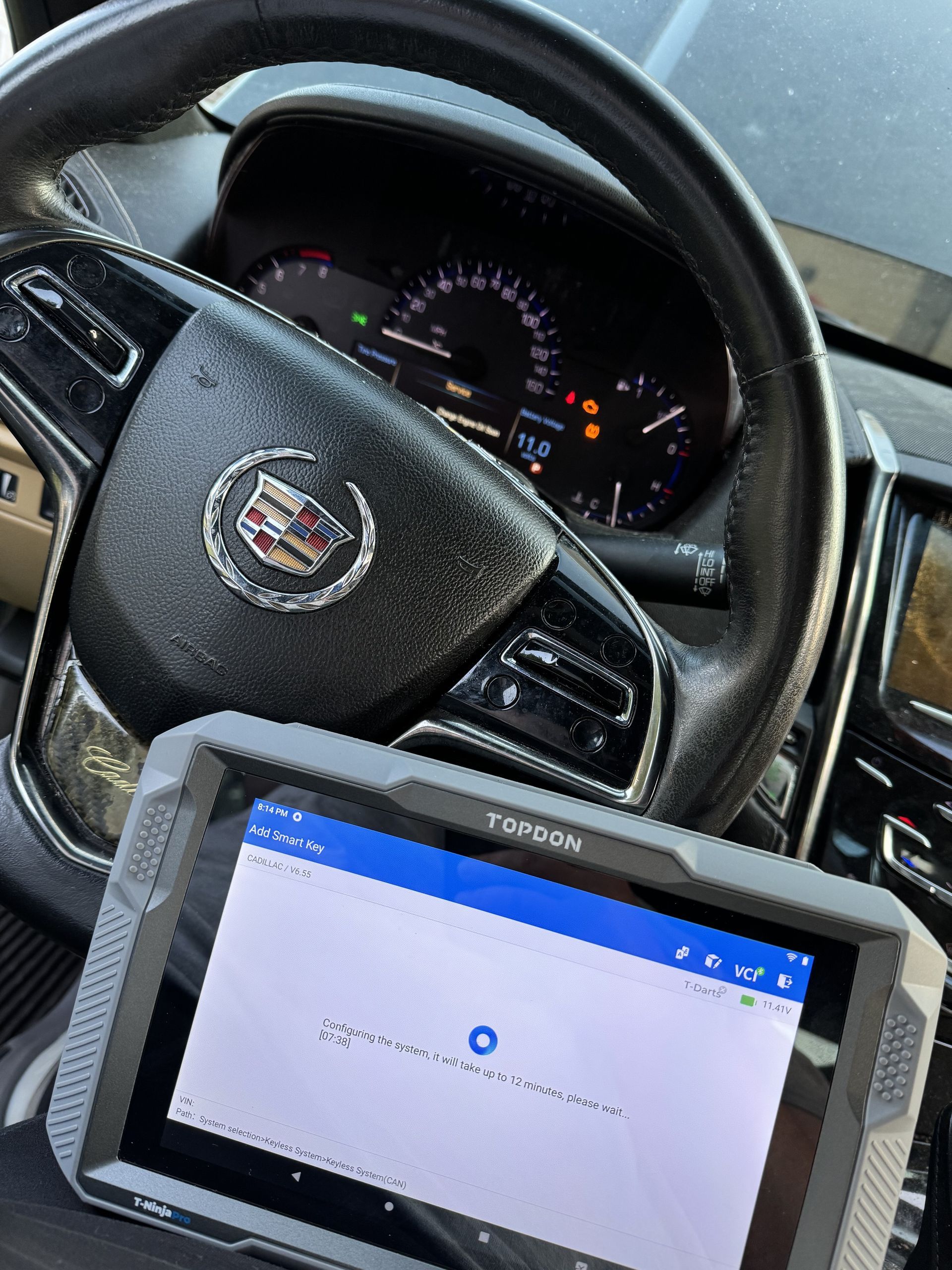 A tablet is sitting on the steering wheel of a car.