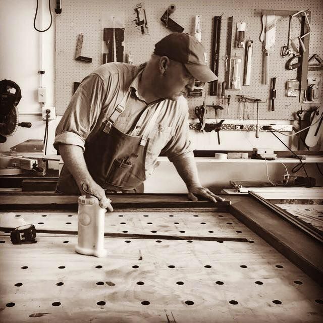 a man in an apron is working on a piece of furniture