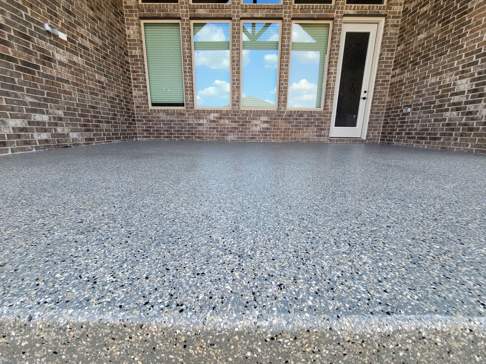 a patio with a brick wall and a sliding glass door .