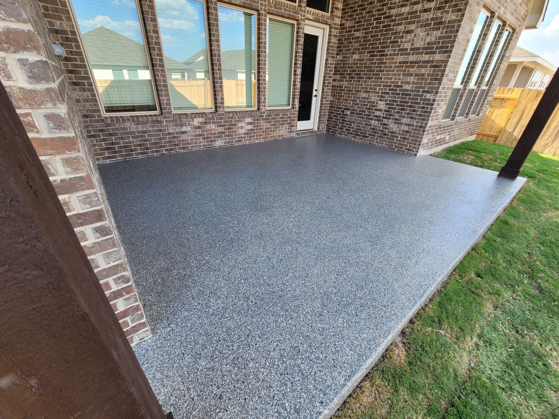 a patio with a brick wall and a concrete floor in front of a house .