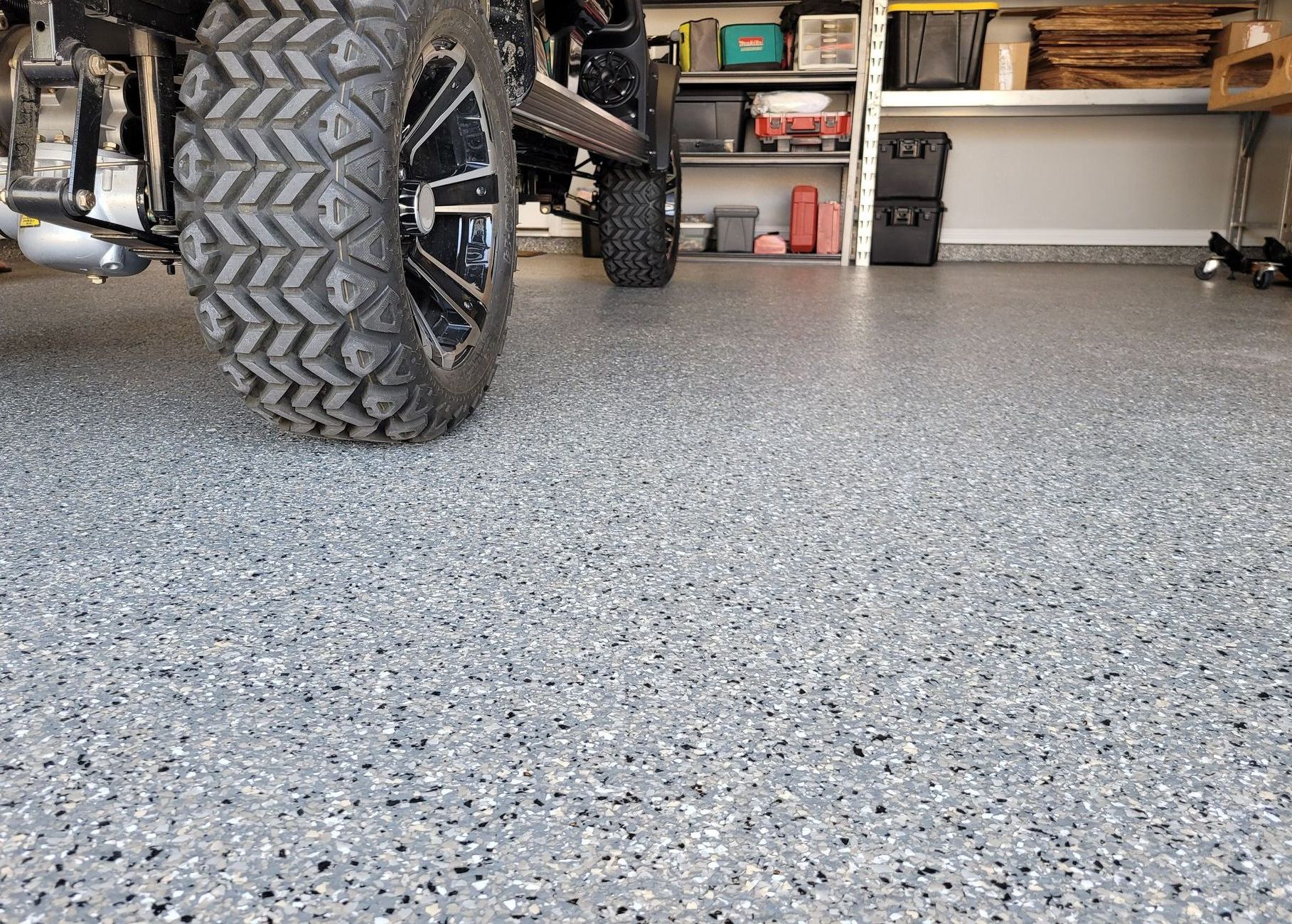 a golf cart is parked in a garage with a new polyaspartic concrete floor coating.