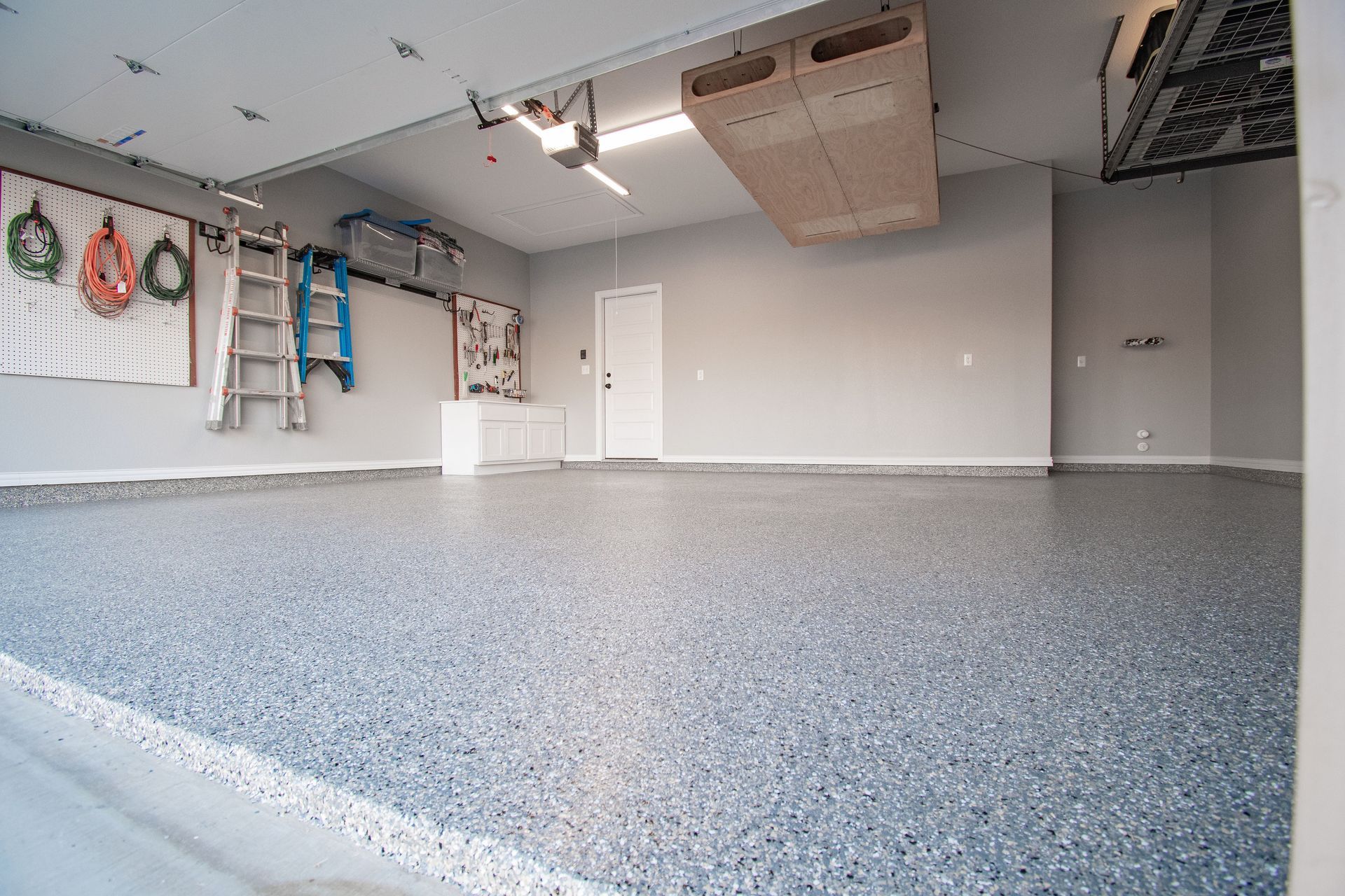 a garage with a concrete floor and a ladder hanging from the ceiling