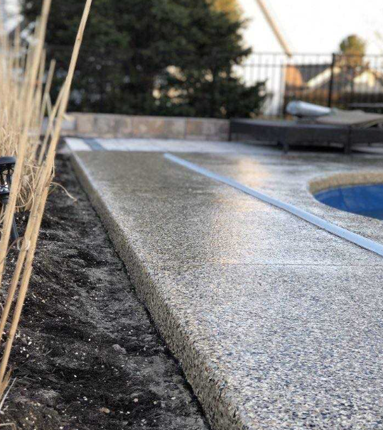 a close up of a polyaspartic coated walkway next to a pool
