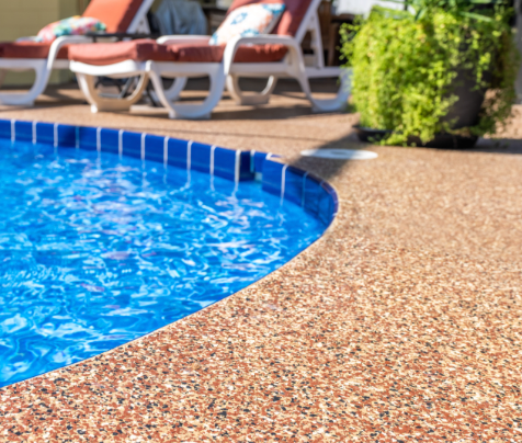 a swimming pool with blue tiles and chairs around it .