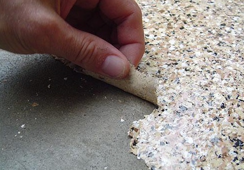a person is peeling off a piece of epoxy flooring .