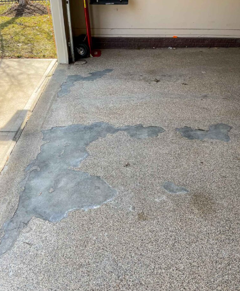 a garage floor with a lot of peeling epoxy