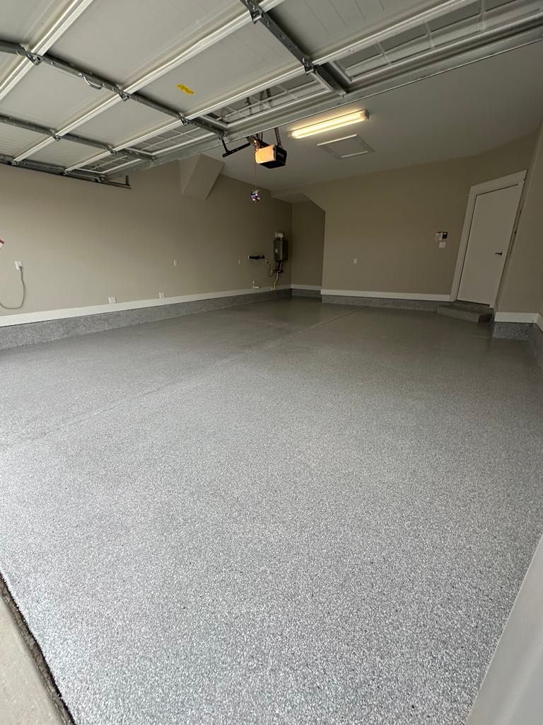 A garage with a gray concrete floor and a garage door opener.
