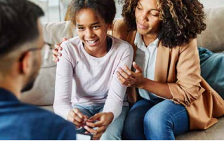 Two women smiling and talking with a man in a casual indoor conversation