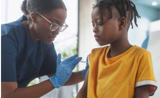 Healthcare worker in blue gloves checks a child’s arm while seated in a bright clinic.