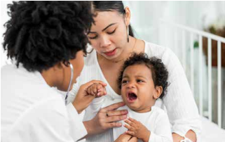Doctor examining a crying baby while a parent holds them outdoors on a porch