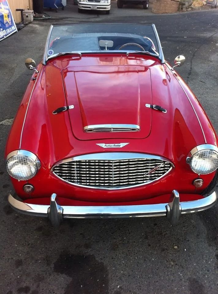Red classic convertible car with chrome details, front view.
