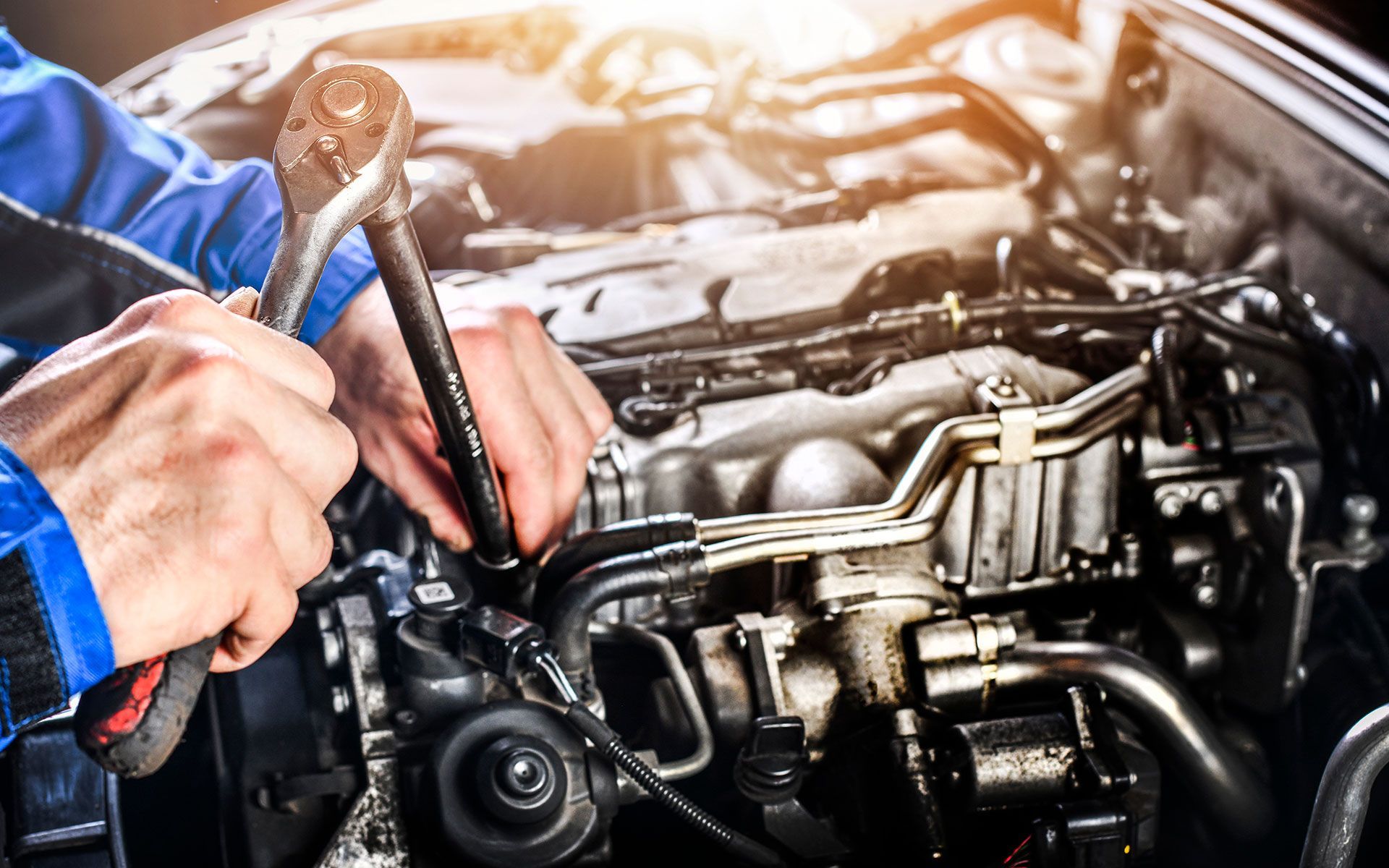 Mechanic working on a car engine with a wrench.