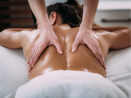 Person receiving a back massage with a handheld device on a spa table Person receiving a back massage with a handheld device on a spa table