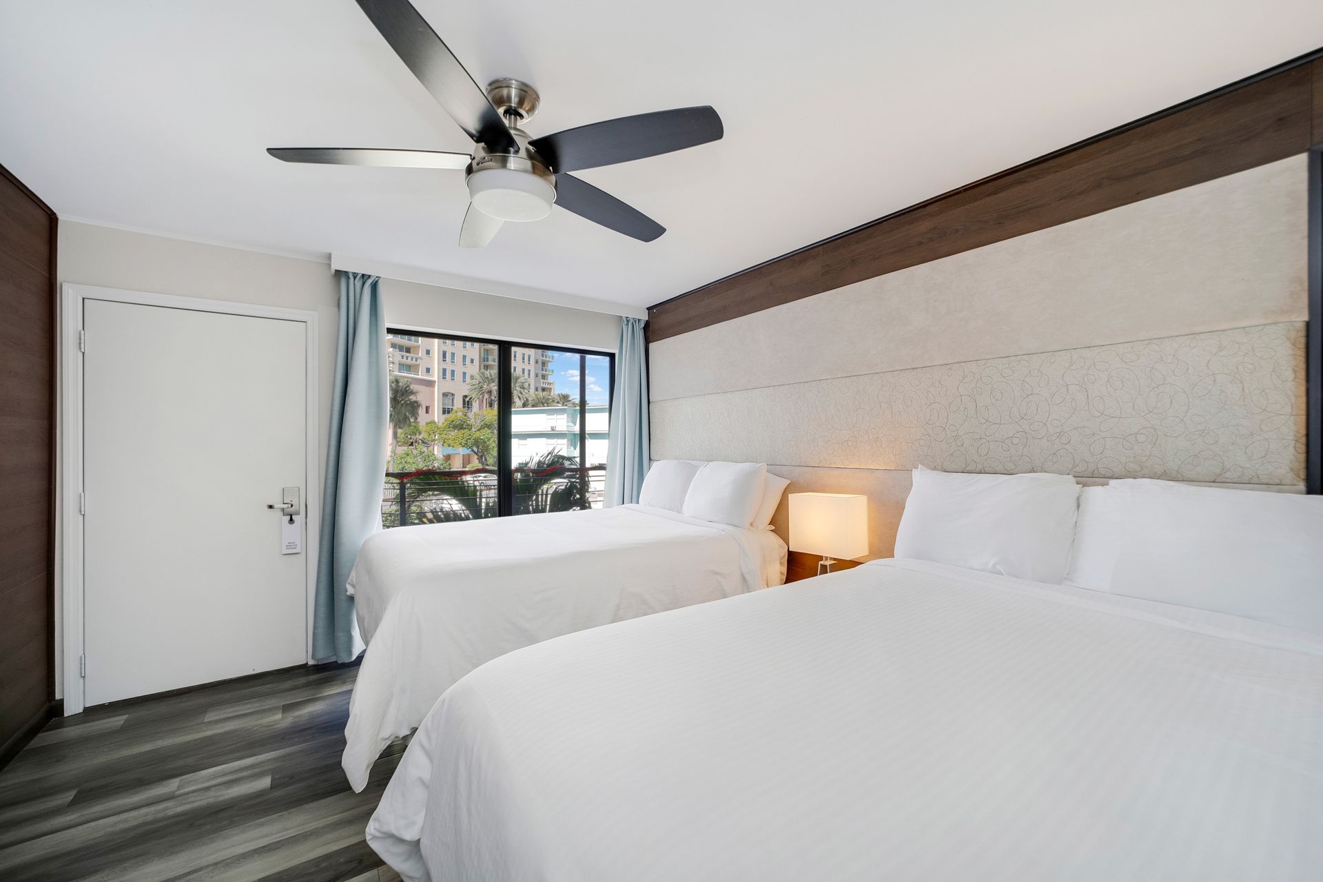 Hotel room with two white beds, a window, and a ceiling fan.