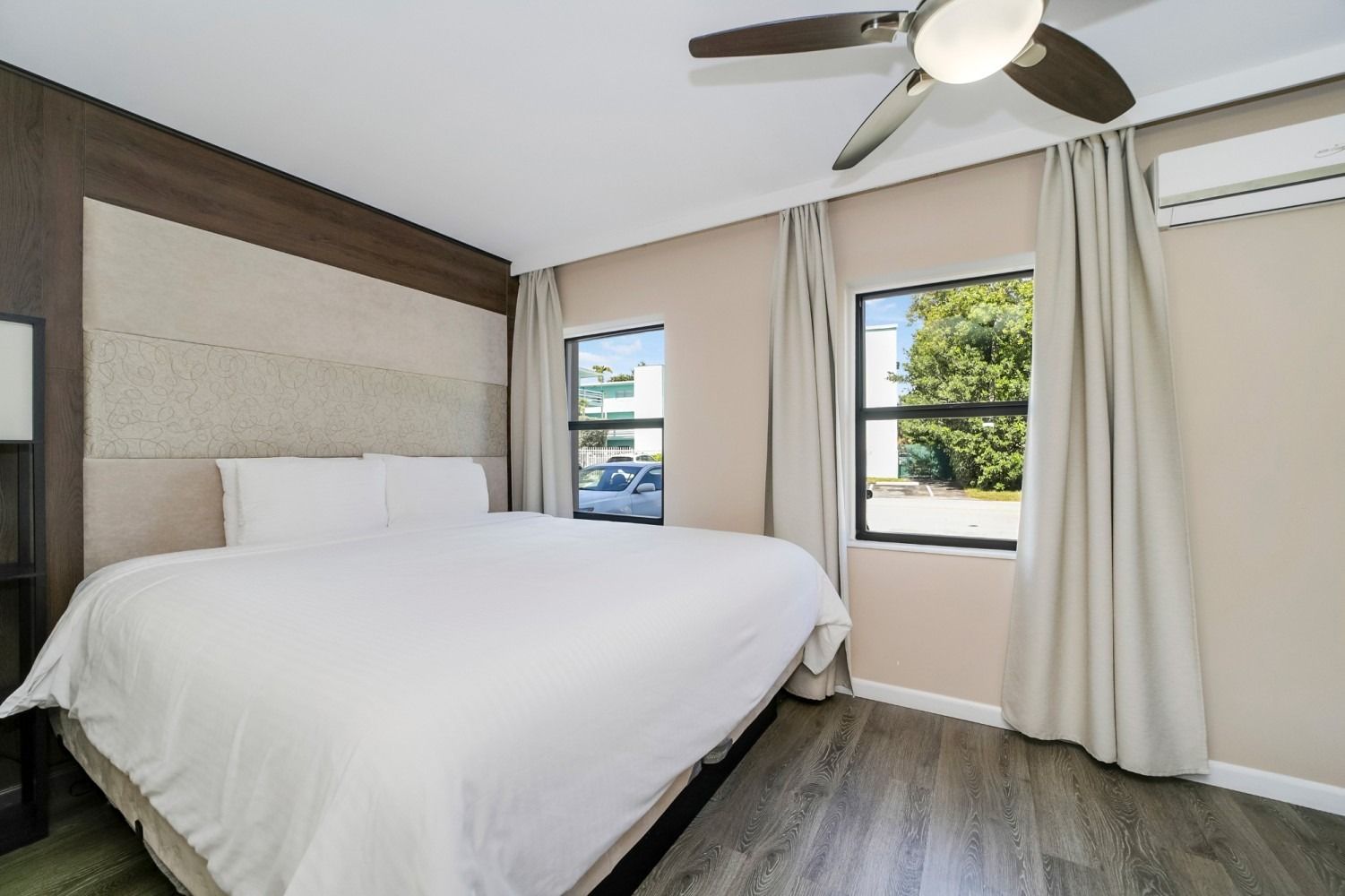 Bedroom with a bed, two windows, curtains, and a ceiling fan.