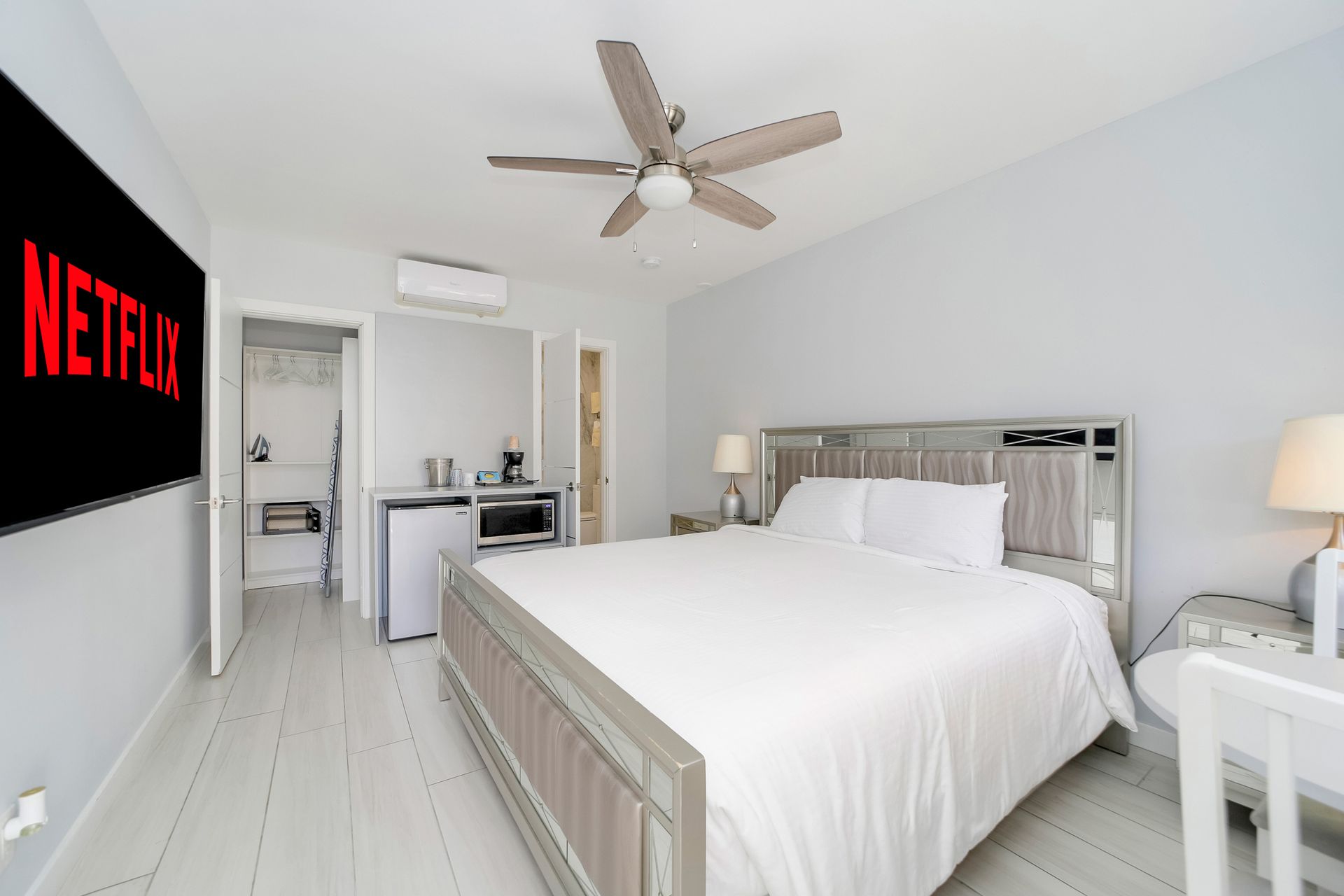 Bedroom with king bed, Netflix screen, small fridge, microwave, and desk.