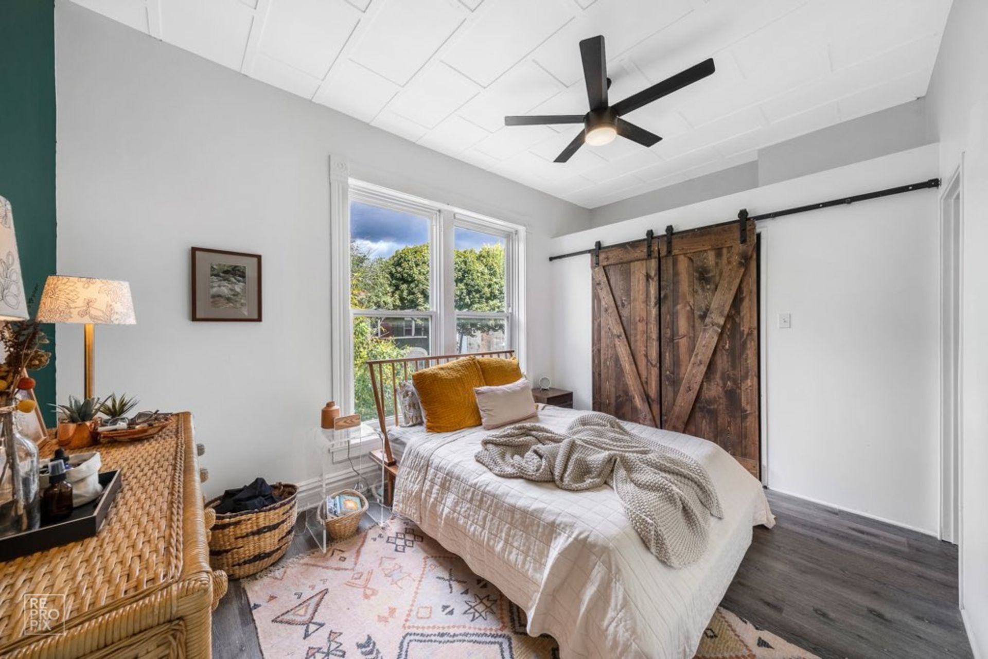A bedroom with a sliding barn door and a ceiling fan.
