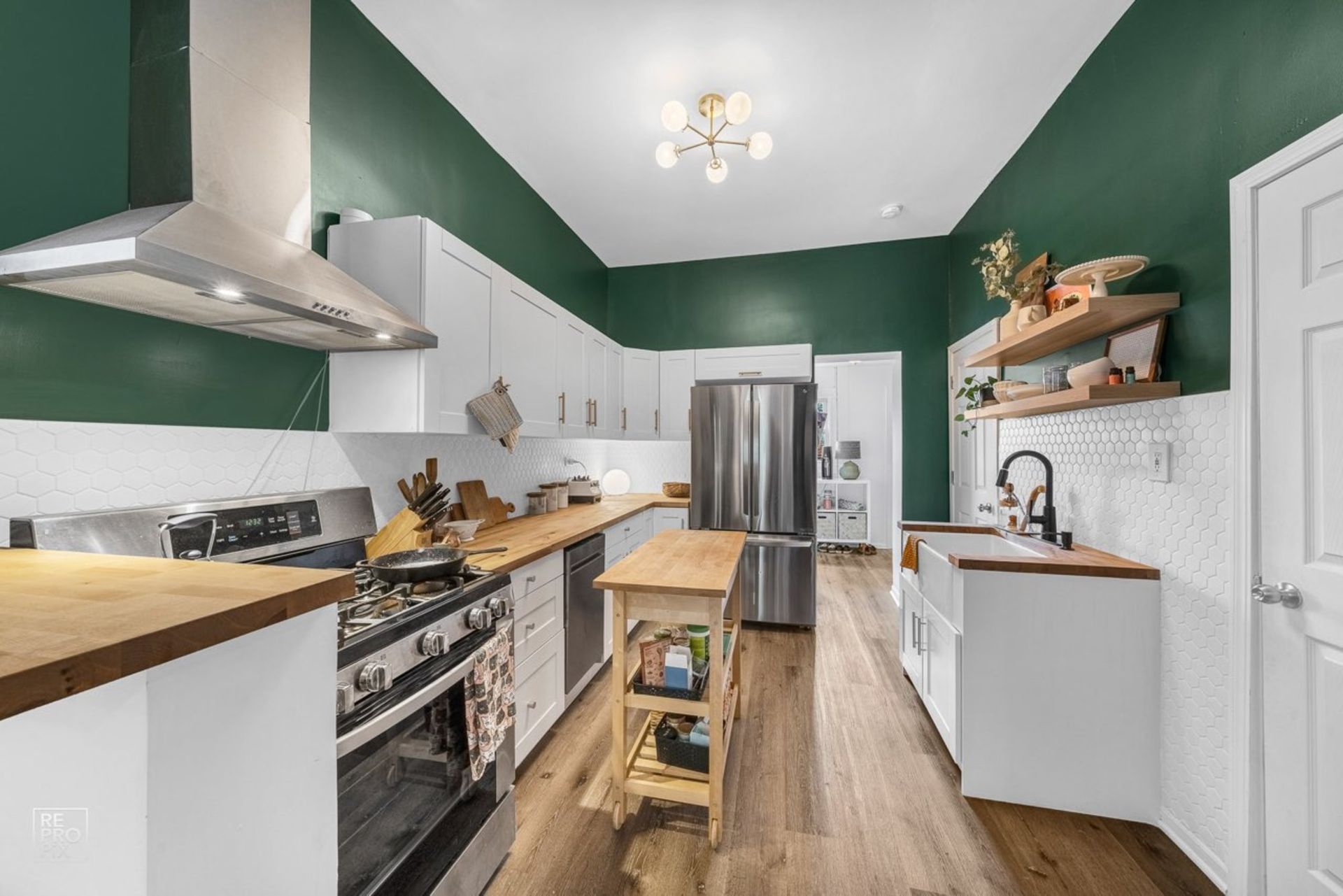 A kitchen with green walls and white cabinets and stainless steel appliances.