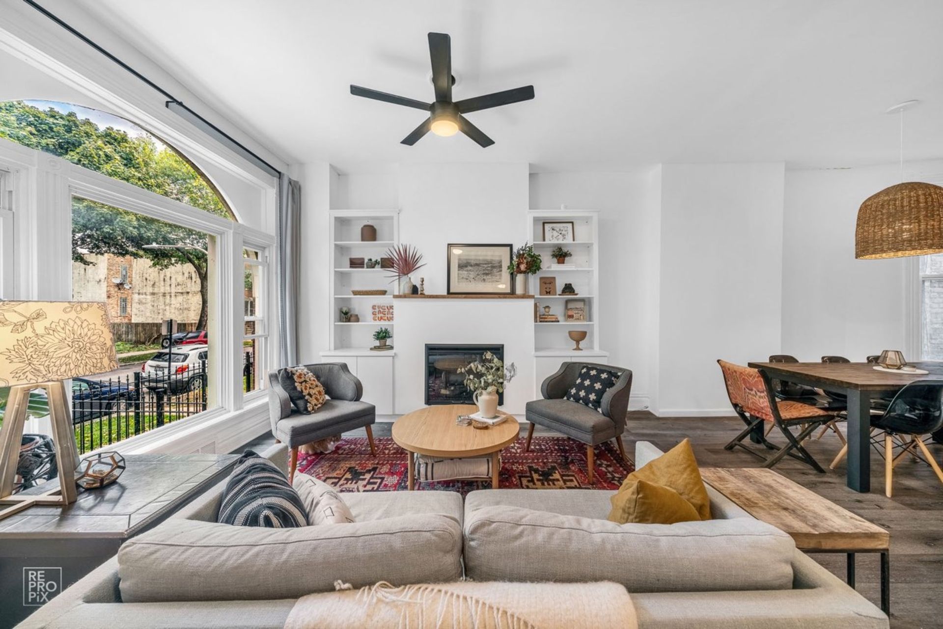 A living room with a couch , chairs , a table and a ceiling fan.