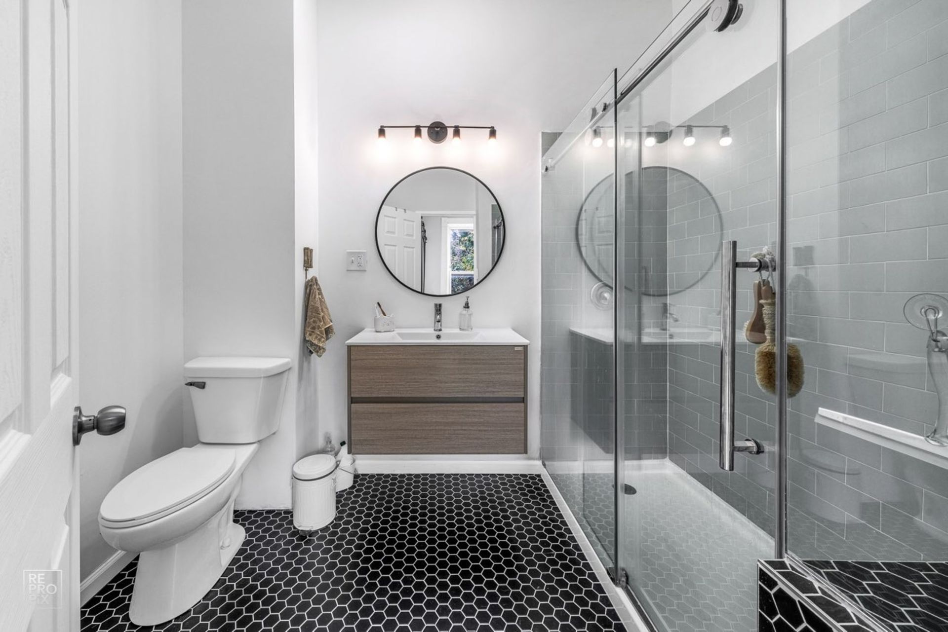 A bathroom with a toilet , sink , shower and mirror.