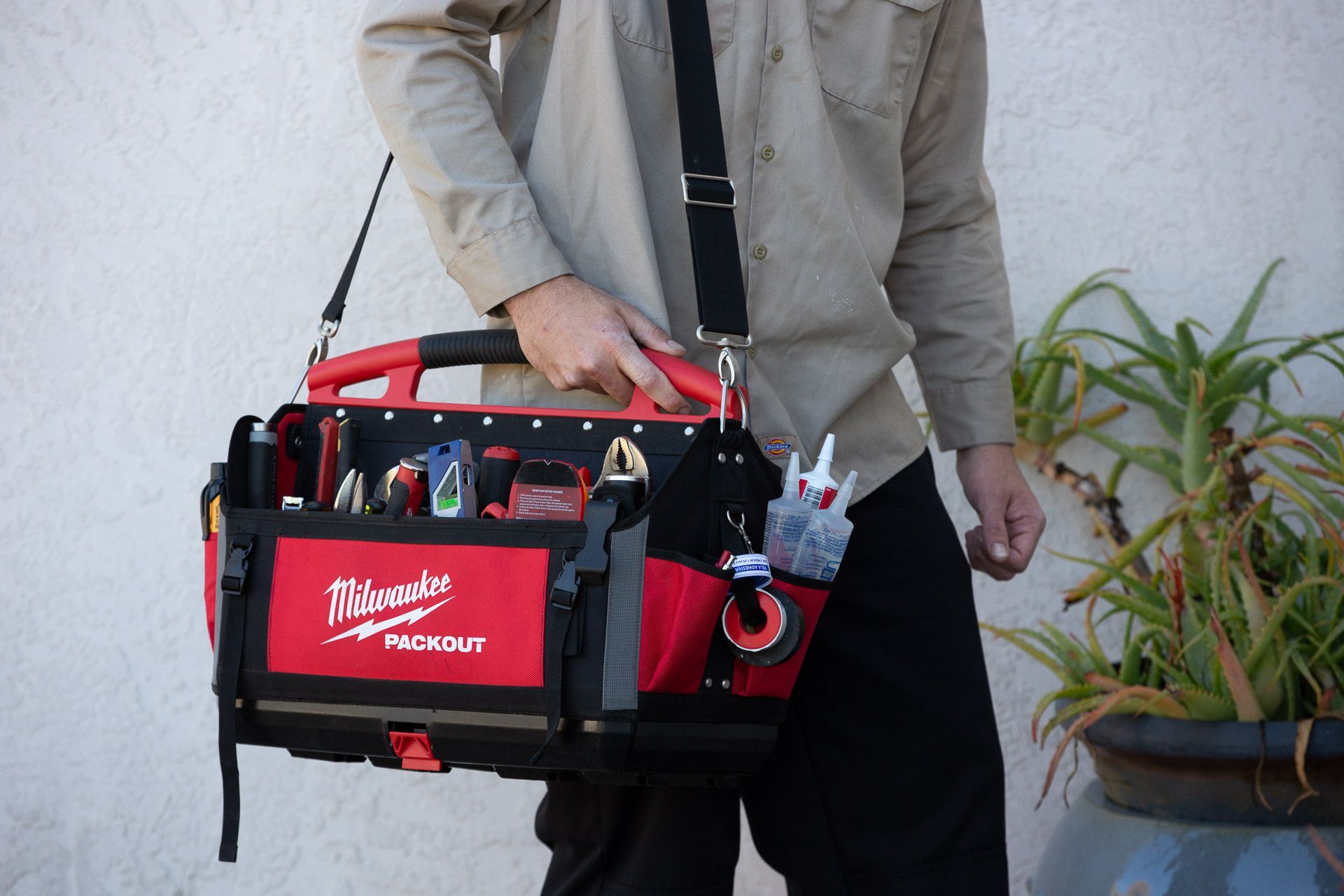 A man is carrying a tool bag on his shoulder.