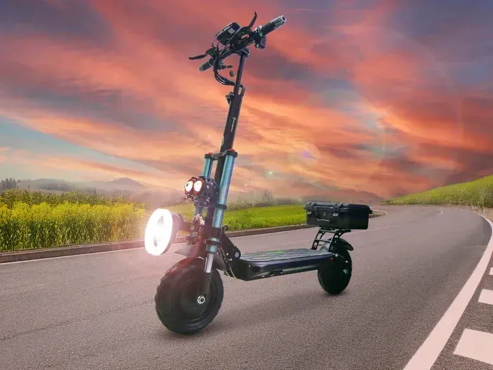 Patinete eléctrico negro en una carretera asfaltada con un faro brillante; cielo de atardecer en el fondo.