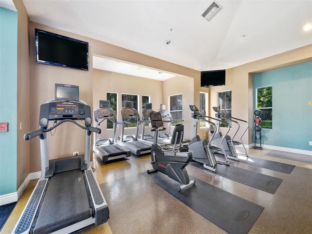 Interior community fitness center with multiple treadmills and ellipticals.