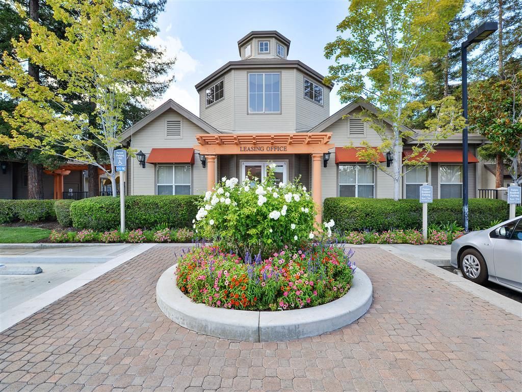 Exterior view of the leasing office with a circular flower bed and surrounding landscaping.
