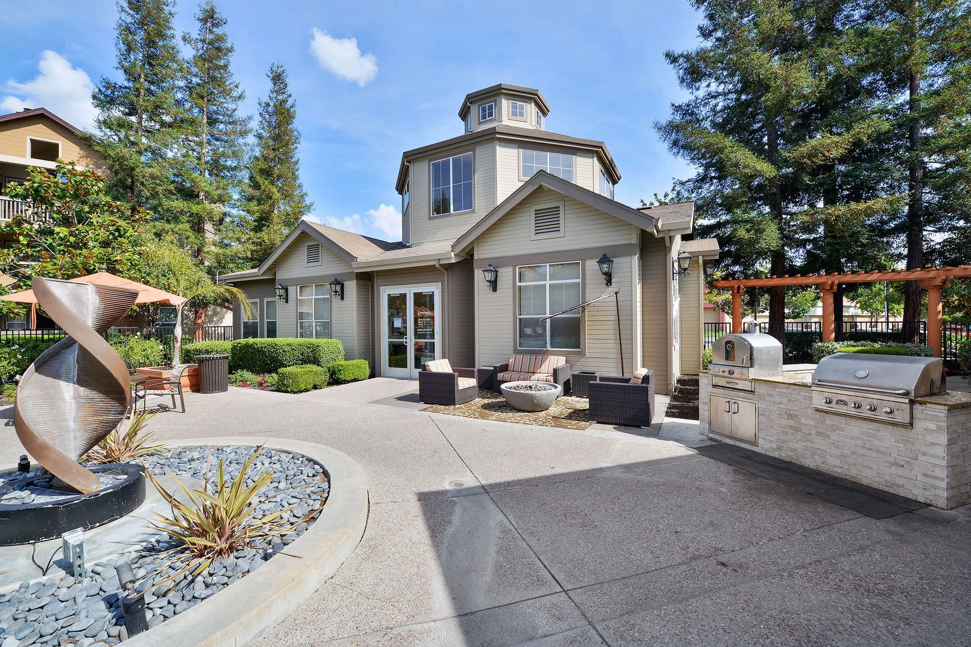 Outdoor community center with a rotunda, grills, seating, and sculpture.