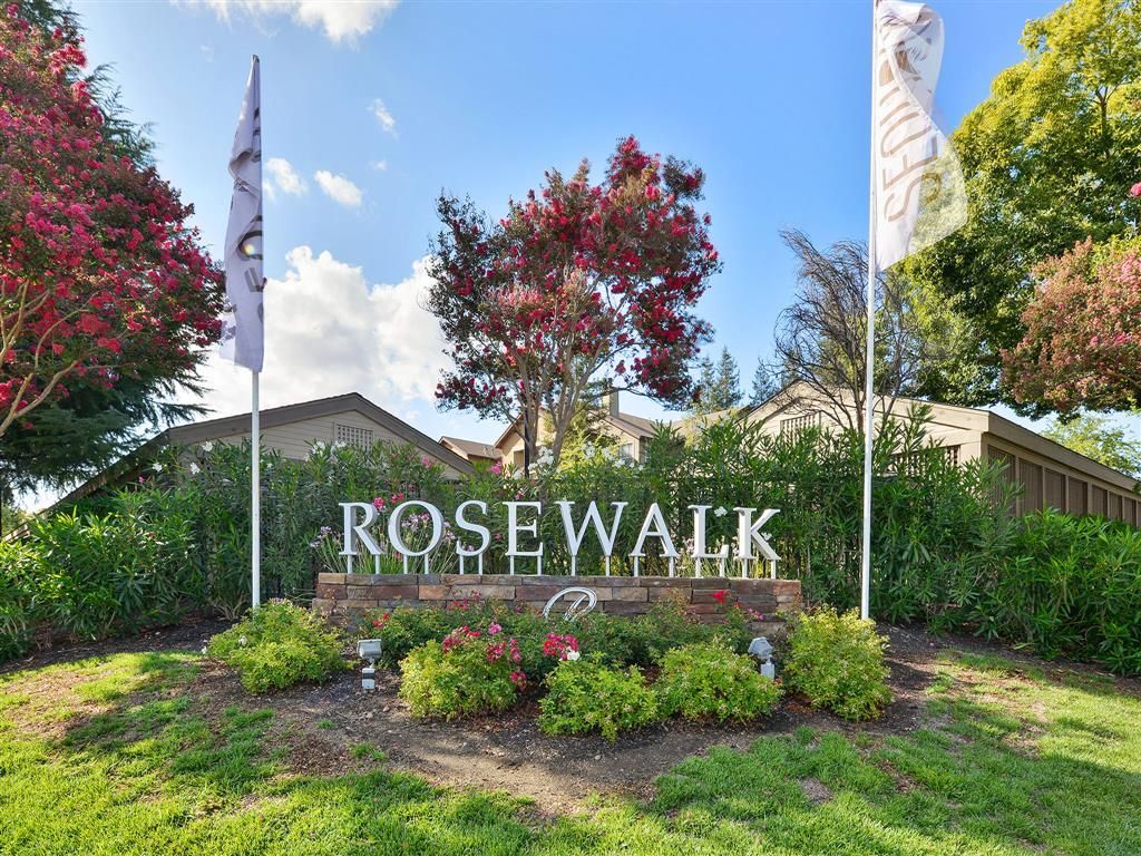 Rosewalk community entrance sign with landscaped shrubbery and flags
