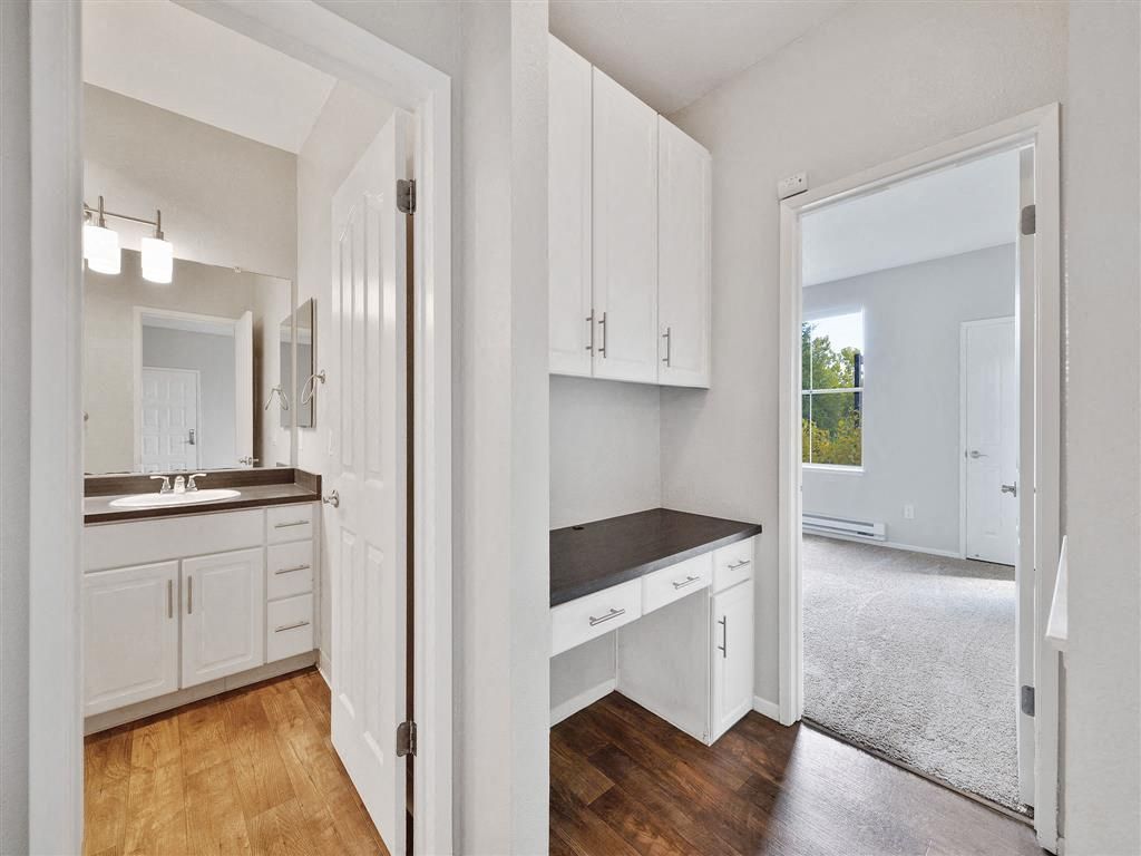 Interior view of a small apartment with a built-in desk and a bathroom doorway.
