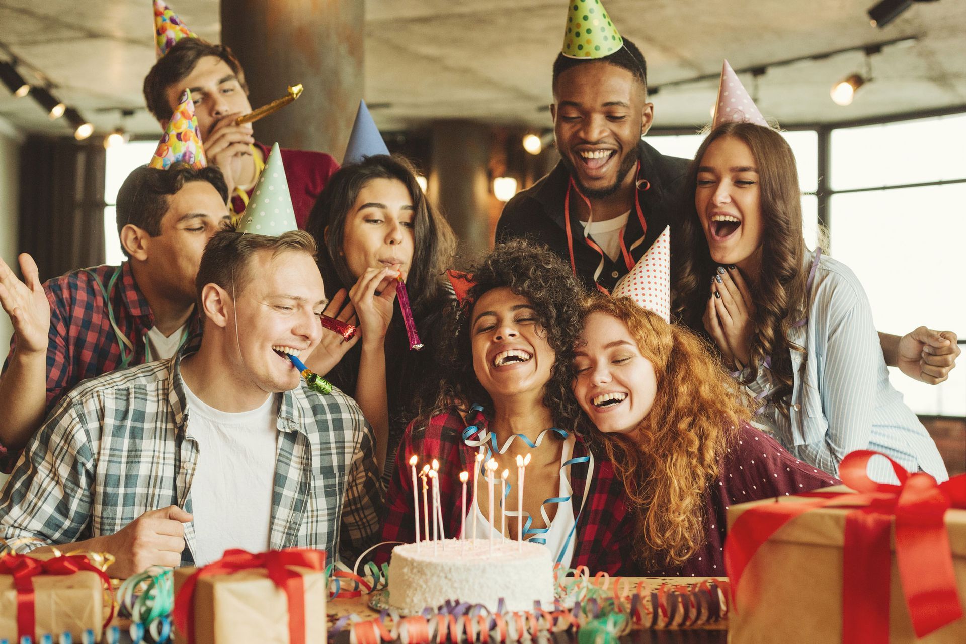 A group of people are celebrating a birthday with a cake and gifts.