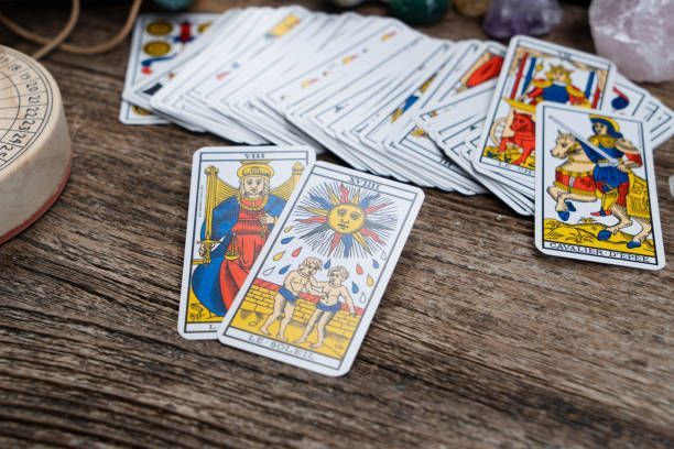 A pile of tarot cards sitting on top of a wooden table.