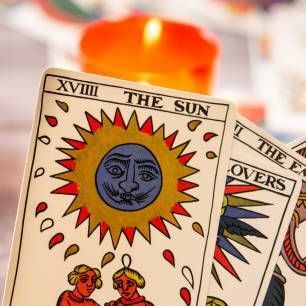 A close up of three tarot cards with a candle in the background.