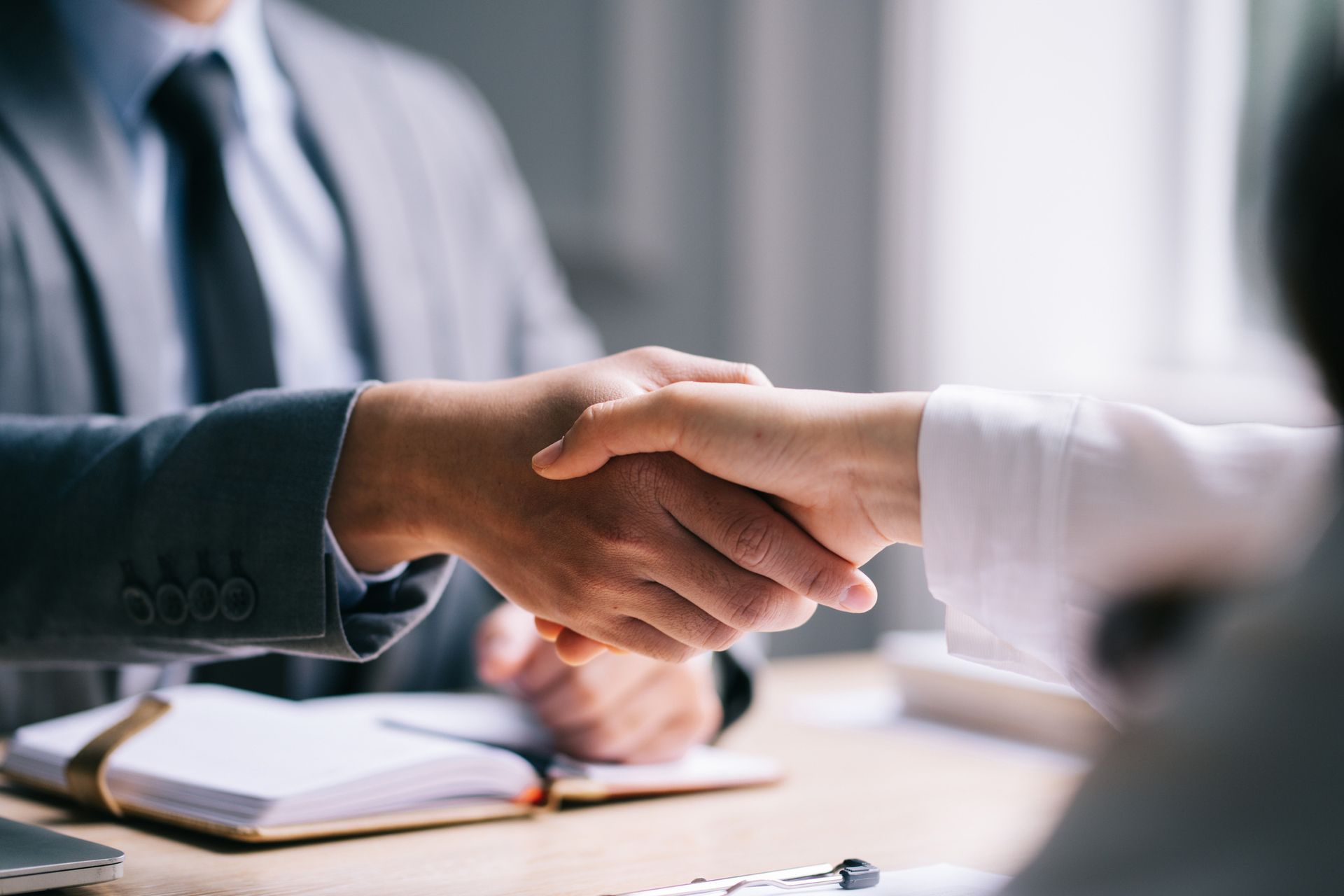 A man in a suit and tie is shaking hands with a woman in a white shirt.