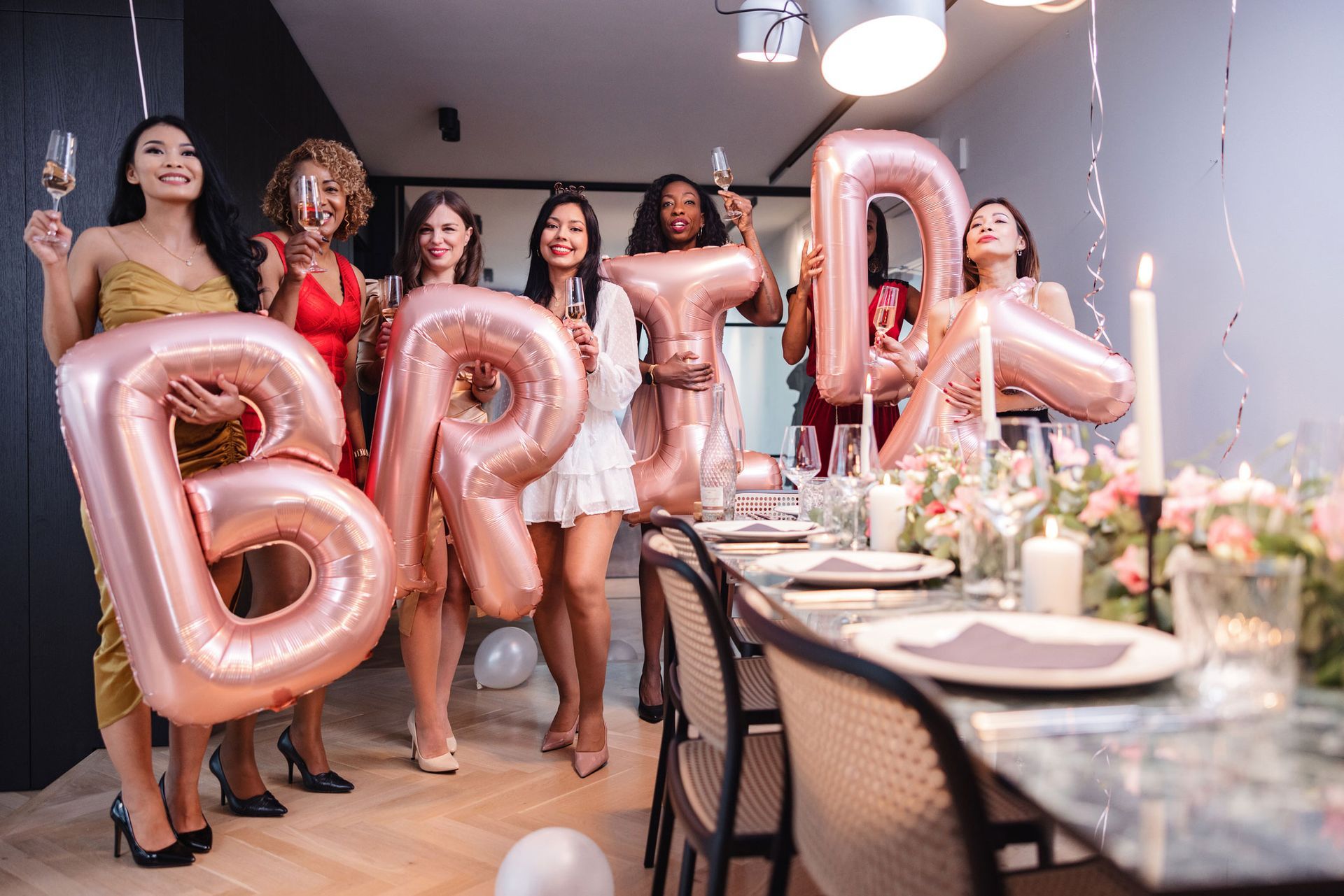 A group of women are holding balloons that spell out the word bride.